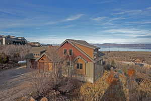 View of side of property featuring a shingled roof and a water view