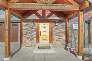 Doorway to property featuring stone siding and a garage