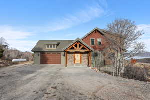 Craftsman house with driveway, an attached garage, a shingled roof, and stone siding