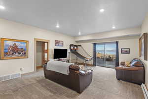 Living room with light colored carpet, a baseboard radiator, and recessed lighting