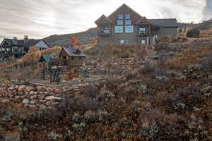 Back of house featuring a playground, a patio, a balcony, and a mountain view