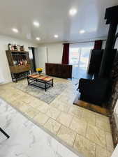 Living area with a wood stove, light marble finish floors, and recessed lighting