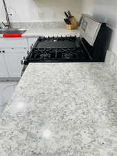 Kitchen view of gas range and white cabinetry