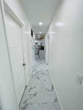 Corridor with light marble finish floors and recessed lighting