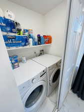 Laundry area with light marble finish flooring and washer and clothes dryer