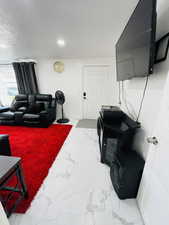 Living area with a textured ceiling and light marble finish floors