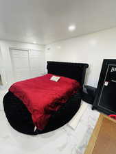 Bedroom with light marble finish floors, recessed lighting, and a closet