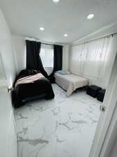 Bedroom with marble look tile flooring, a textured ceiling, and recessed lighting