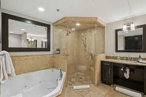 Bathroom with a tub with jets, vanity, a shower stall, and recessed lighting