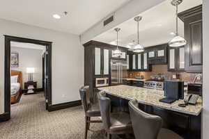 Kitchen with glass insert cabinets, a kitchen breakfast bar, light stone countertops, a peninsula, and decorative backsplash