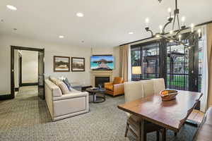 Carpeted dining room with a glass covered fireplace, recessed lighting, and a chandelier