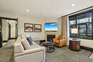Living area with recessed lighting, a glass covered fireplace, and carpet