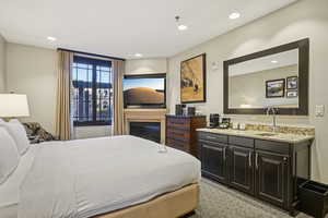 Bedroom with recessed lighting, a glass covered fireplace, and light carpet