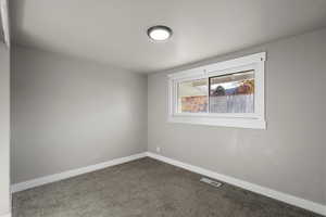 Carpeted spare room featuring baseboards