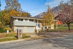 Split entry home featuring brick siding, a mountain view, driveway, and a garage