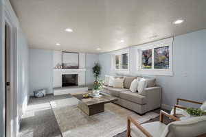 Carpeted living room featuring a brick fireplace, recessed lighting, and a textured ceiling