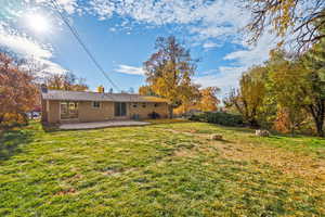 Back of house featuring brick siding, a chimney, a yard, and a patio area