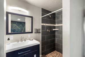 Primary bath with a stall shower, vanity, and a textured ceiling