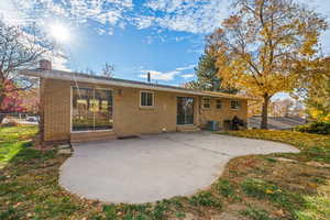 Rear view of house with a patio area, brick siding, and a chimney
