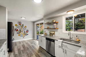 Kitchen with backsplash, stainless steel dishwasher, vinyl floors, freestanding refrigerator, and a textured ceiling