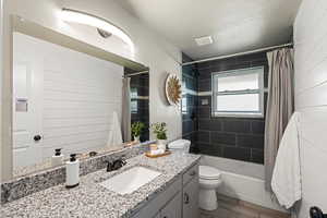 Bathroom with vanity, shower / bath combo, wood tiled floors, and a textured ceiling