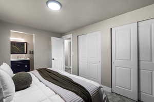 Bedroom with two closets, carpet, and a textured ceiling