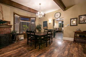 Dining area featuring beam ceiling, a fireplace and dark wood-style flooring