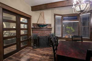 Home office with beamed ceiling, dark wood-style flooring, a chandelier, and a fireplace