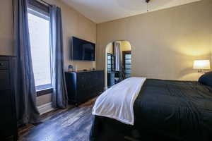 Bedroom with dark wood finished floors,  arched walkways and wide baseboards