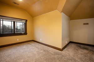 Carpeted room featuring vaulted ceiling, and baseboards.