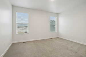 Spare room featuring light carpet and baseboards
