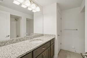 Full bath with light tile patterned floors, vanity, and a shower