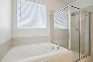 Bathroom featuring a garden tub and a shower stall