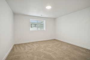 Empty room with light colored carpet and baseboards