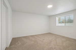 Spare room featuring light carpet and baseboards