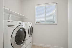 Laundry room featuring light tile patterned flooring and washing machine and clothes dryer