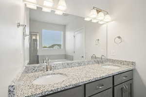 Full bathroom featuring double vanity, a garden tub, and a shower stall