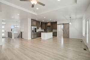 Unfurnished living room with healthy amount of natural light, a barn door, light wood-style floors, and recessed lighting