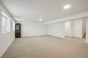 Basement with light carpet, stairway, and recessed lighting