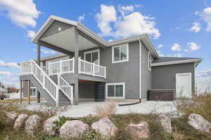 Back of property featuring stucco siding, a patio area, a jacuzzi, a deck, and stairs