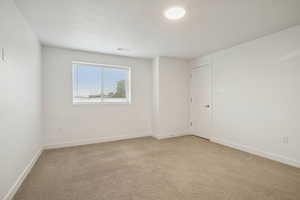 Spare room featuring light colored carpet and baseboards