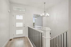 Entryway with light wood-style floors and a chandelier