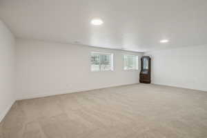 Empty room with light colored carpet and recessed lighting