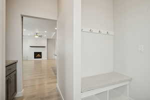 Mudroom featuring a warm lit fireplace, recessed lighting, light wood-type flooring, and a ceiling fan