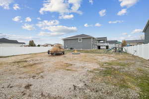 Rear view of house featuring a fenced backyard, an outdoor fire pit, and a playground