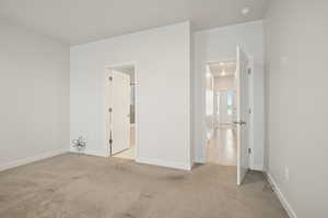 Unfurnished bedroom featuring light colored carpet and ensuite bathroom
