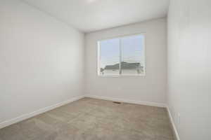 Spare room with light carpet and baseboards