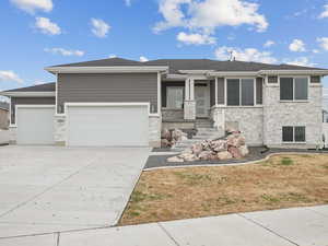 Prairie-style home with stone siding, concrete driveway, an attached garage, and a shingled roof