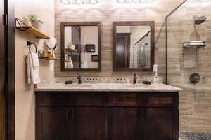 Bathroom featuring a shower stall and double vanity