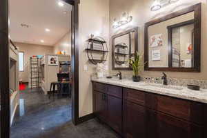 Full bath featuring double vanity, recessed lighting, and concrete floors